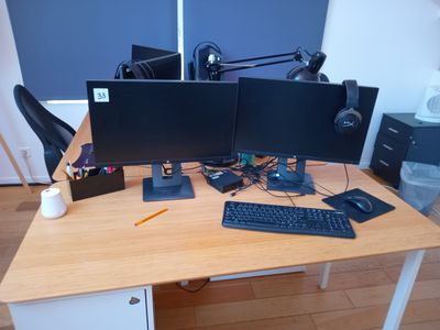 un bureau sur lequel sont posés deux écrans d'ordinateur et un clavier