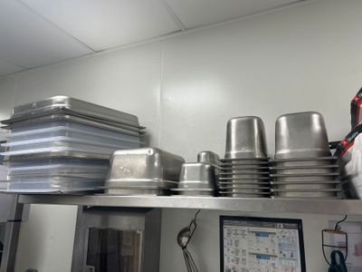 de nombreuses casseroles et poêles rangées sur une étagère dans une cuisine
