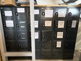 Plusieurs casiers métalliques sont alignés dans une pièce où se trouvent des cartons