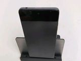 the back of a black cell phone sitting on top of a metal stand