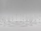 six verres à vin transparents sont alignés sur une surface blanche