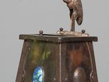 a bronze statue of a bird sitting on top of a table