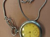 a yellow pocket watch on a chain on a table