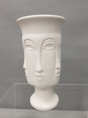 un vase blanc orné d'un visage, exposé dans une vitrine
