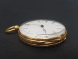 a gold pocket watch on a black surface