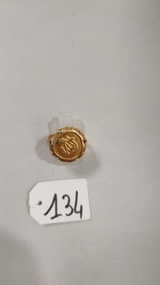 un gros plan d'une petite bague en or sur une surface blanche