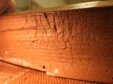 a close up of a piece of wood with a person holding a knife