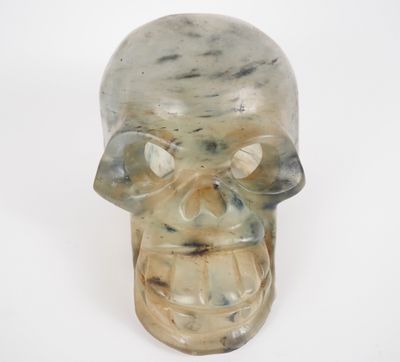 a glass skull with a face on a white surface
