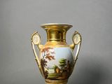a gold vase with a painting on it sitting on a table
