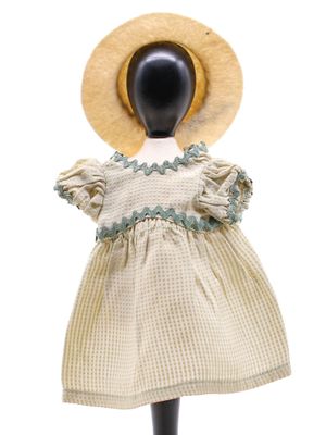 une image représentant une poupée coiffée d'un chapeau et vêtue d'une robe, posée sur un mannequin