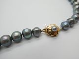 un gros plan sur un collier de perles muni d'un fermoir en or