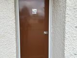 a brown door in the corner of a white building