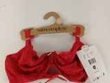 une bralette en dentelle rouge suspendue à un cintre, avec une étiquette de prix