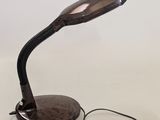 brown desk lamp sitting on top of a wooden table next to a white wall