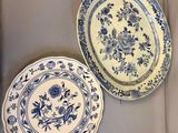 two blue and white plates with floral designs on them on a table