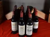 several bottles of wine are lined up on a red table cloth