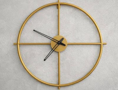 une horloge dorée aux aiguilles noires accrochée à un mur blanc