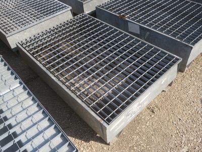 plusieurs grilles en acier sont empilées les unes sur les autres au sol