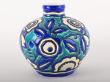 un vase bleu et vert posé sur une surface blanche