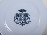 a plate with a coat of arms on it and a stack of plates behind it