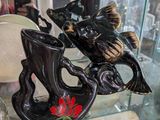 une vitrine en verre sur laquelle sont posés un vase et un poisson