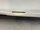 a close up of a white car with rust on the side of it