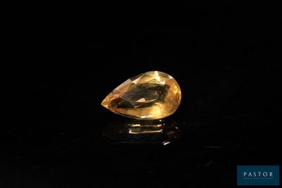 a yellow sapphire stone on a black surface