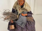 figurine of a woman with a basket of twigs and a watering can