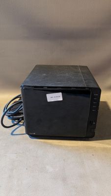 une petite boîte noire posée sur une surface blanche