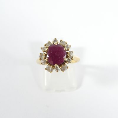 a close up of a gold ring with a ruby stone surrounded by diamonds