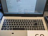 un ordinateur portable posé sur un bureau, à côté d'un bloc-notes