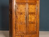 une vieille armoire en bois à deux portes, ornée de sculptures sur la façade