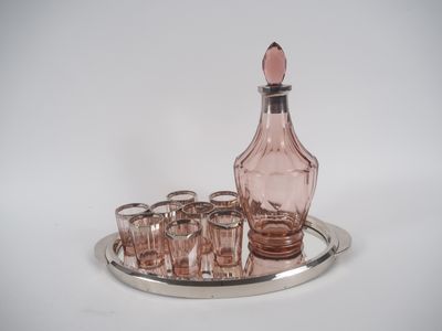 des bouteilles et des verres posés sur un plateau en argent, sur une surface blanche