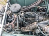 an old green car with a engine in the back