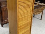 a tall wooden cabinet in a room with a piano in the background