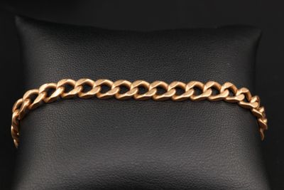 un bracelet en chaîne d'or posé sur un coussin en cuir noir