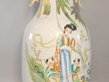 a white vase with a painting on it sitting on a table