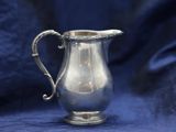 a small silver pitcher sitting on a blue cloth