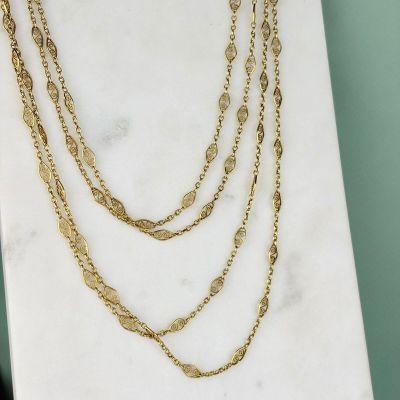 un gros plan d'un collier en or posé sur une surface en marbre