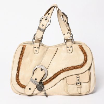 beige leather handbag with metal buckles on a white background