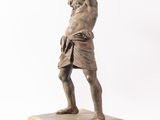 an antique bronze statue of a man holding a hammer in his hand