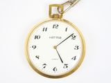 une montre de poche en or à laquelle est accrochée une chaîne sur le côté