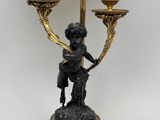 a statue of a boy holding a candelab with three candles on it