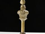a tall brass pole with a bird on top of it