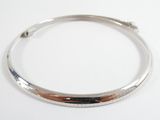 a close up of a silver bang bracelet on a white surface
