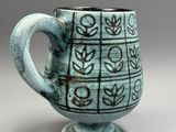 a close up of a cup on a table with a gray background