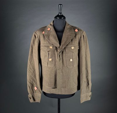 an old military jacket on a mannequin stand on a black background