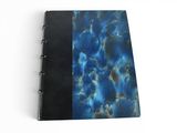 a close up of a blue and black notebook on a white surface