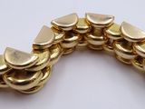 a close up of a gold bracelet on a white surface