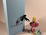 a figurine of a woman in a pink dress next to a blue box